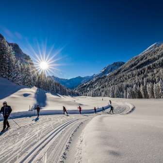 Cross-country skiers enjoy the freshly groomed trail in bright sunshine in Steg, Liechtenstein.