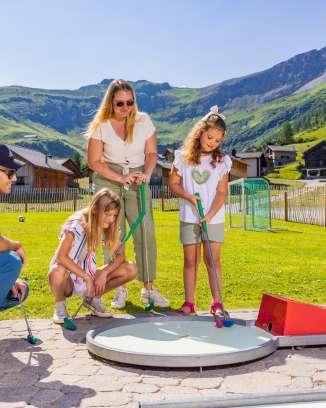 A family plays mini-golf together in the sunny mountain village of Malbun in Liechtenstein