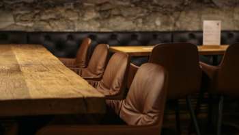 Close-up of a wooden table with comfortable leather chairs in the cozy seating area of the WY Weinbar.
