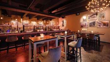 Elegant restaurant interior with dark wood elements, bar area and comfortable chairs in a cozy ambience.