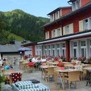 Sunny terrace of the restaurant with covered tables, parasols and views of the Alps.