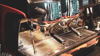 Coffee machine in the restaurant with shiny stainless steel surface and red accents