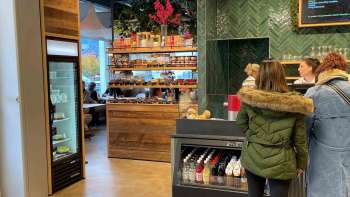 Customers at the checkout, surrounded by inviting wooden decorations and fresh products