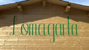 View of the green Lömagarta logo, which is stylishly emblazoned on the wooden façade of the cozy beer garden.