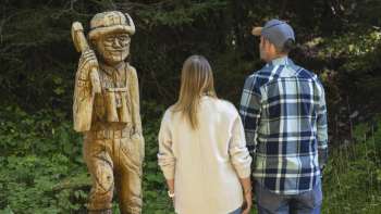 Walkers look at carved wooden figures along the Walser Saga Trail