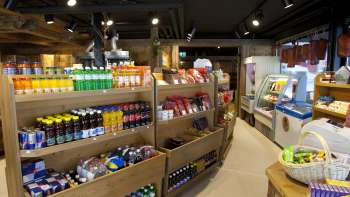 Interior view of the Malbuner Läderli with wooden shelves full of regional products, drinks and snacks.