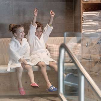 Two children in bathrobes enjoy the wellness area at the Hotel Gorfion - family vacation with a feel-good factor in Malbun.
