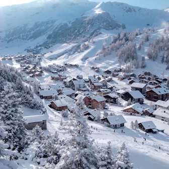 Snow-covered houses and ski slopes in the alpine winter village of Malbun, nestled in a stunning mountain landscape.