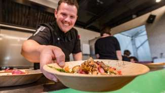 Chef serves a plate of regional dishes at the Genussfestival Vaduz, Liechtenstein - culinary event with a focus on enjoyment
