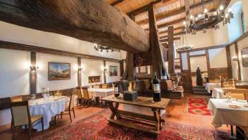Rustic dining room with historic wooden beams, fireplace and covered tables in the Torkel restaurant.