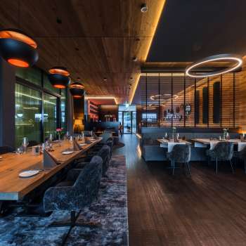 Elegant dining room with modern lighting elements and wood paneling on the walls.