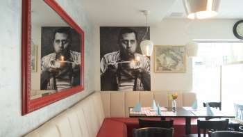 Cozy seating area in the Made in Italy restaurant with stylish mural and red mirror. Cozy seating area in the Made in Italy restaurant with stylish mural and red mirror.