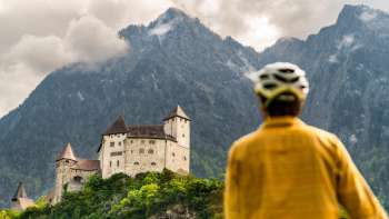 Mountain biker in yellow jacket looks down on Gutenberg Castle