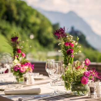 Elegantly laid table with flower arrangements on a terrace with a view of the Alps - the perfect backdrop for celebrations or romantic dinners in Liechtenstein