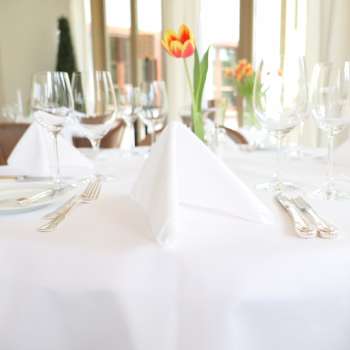 Festive table setting with white tablecloth and fresh tulip