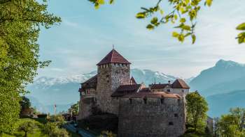 Picturesque view of Vaduz Castle, nestled in green hills and forests.