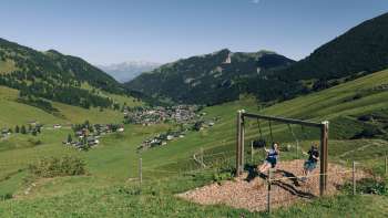 A family enjoys swinging together on the Swing Trail in Malbun