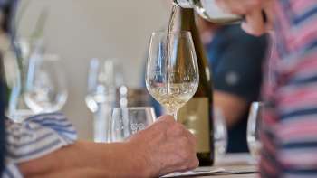 A glass of white wine is poured during a guided tasting.