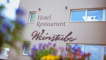 Meadow view of the Weinstube restaurant with flowers in the foreground 