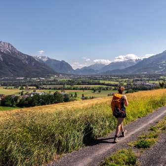 Woman hiking on a dirt road with a panoramic view over the Rhine Valley in Liechtenstein