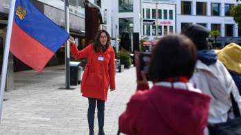 City guide with Liechtenstein flag welcomes tourist group in Vaduz