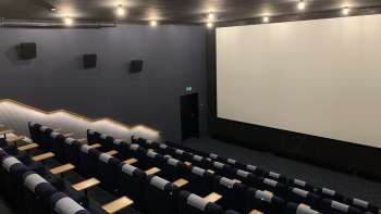 lick of the big screen at Skino Schaan, with rows of comfortable seats in a dark design.