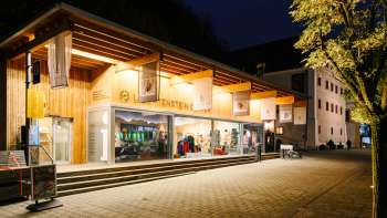 Modern visitor center with glass front in Vaduz at night, invitingly illuminated.