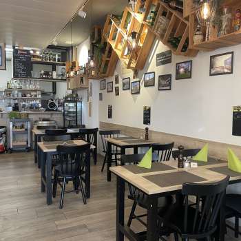 Cozy restaurant interior with modern wooden tables, green napkins and decorative elements
