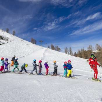 Ski instructor at Malbi Park Malbun motivates children on the practice slope - perfect environment for their first turns in the snow