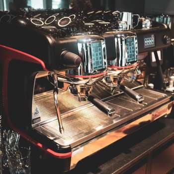 Coffee machine in the restaurant with shiny stainless steel surface and red accents
