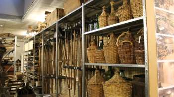 Shelves with traditional tools, wicker bottles and everyday objects