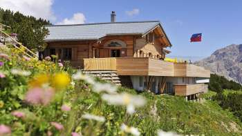 Exterior view of the Sareis Bergrestaurant with flowers in the foreground and mountains in the background