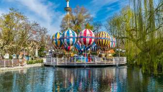 Overview of the Liechtenstein balloon ride at Europa-Park, with colorful balloons over a lake, surrounded by trees and attractions