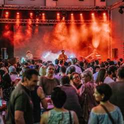 Concert by the band Baba Shrimps at the FL1.LIFE Festival with red stage lighting and a large audience
