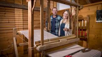 A couple looks at a functioning historical loom in the Walser Museum Triesenberg in Liechtenstein, surrounded by wood paneling