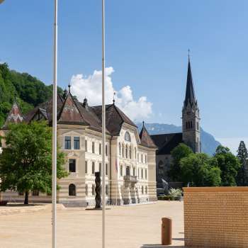  View through a round arch of the government district in Vaduz with the parliament building and St. Florin's Cathedral.