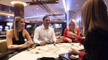 Friendly atmosphere at the gaming table: three guests chat with the croupière in the stylishly furnished Casino Schaanwald.