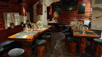 View of a rustic restaurant with wooden furniture, green decorated tables and candles