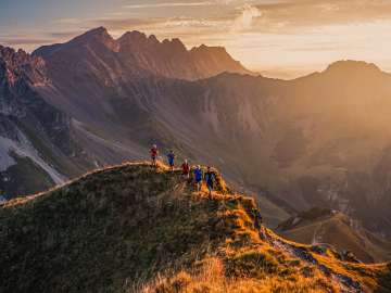 Group of trail runners on a mountain ridge near Malbun, Liechtenstein, in the warm light of the sunset with a view of the Alps