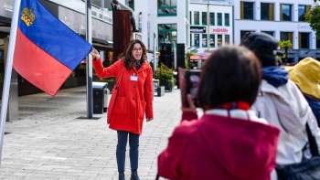 City guide with Liechtenstein flag welcomes tourist group in Vaduz