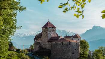 Picturesque view of Vaduz Castle, nestled in green hills and forests.