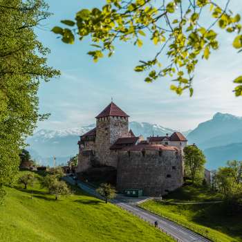 Picturesque view of Vaduz Castle, nestled in green hills and forests.