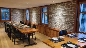Stylish dining room with long wooden tables, stone walls and modern decoration