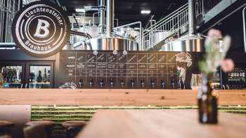Modern brewery bar with large logo and shiny taps in the foreground.