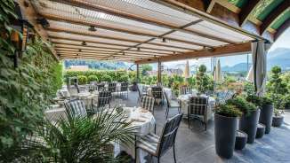 Covered terrace of the Restaurant Torkel in Vaduz, surrounded by plants and with a view of the Alps