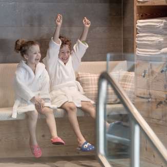 Two children in bathrobes enjoy the wellness area at the Hotel Gorfion - family vacation with a feel-good factor in Malbun.