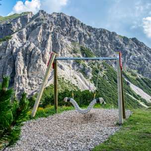 Hanging swing on the Swing Trail Malbun with a view of steep rock faces and alpine landscape in Liechtenstein