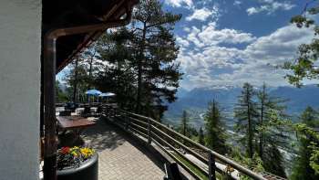"Sun terrace with panoramic views over the Rhine Valley on a clear day and cozy Alpine-style seating at the Berggasthaus Matu