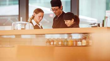 Three employees of the café in the Liechtenstein Art Museum, working together at the counter and exchanging ideas.