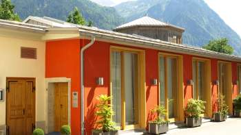 Exterior view of the Gasometer Cultural Center with colorful facade and Alpine panorama in the background.